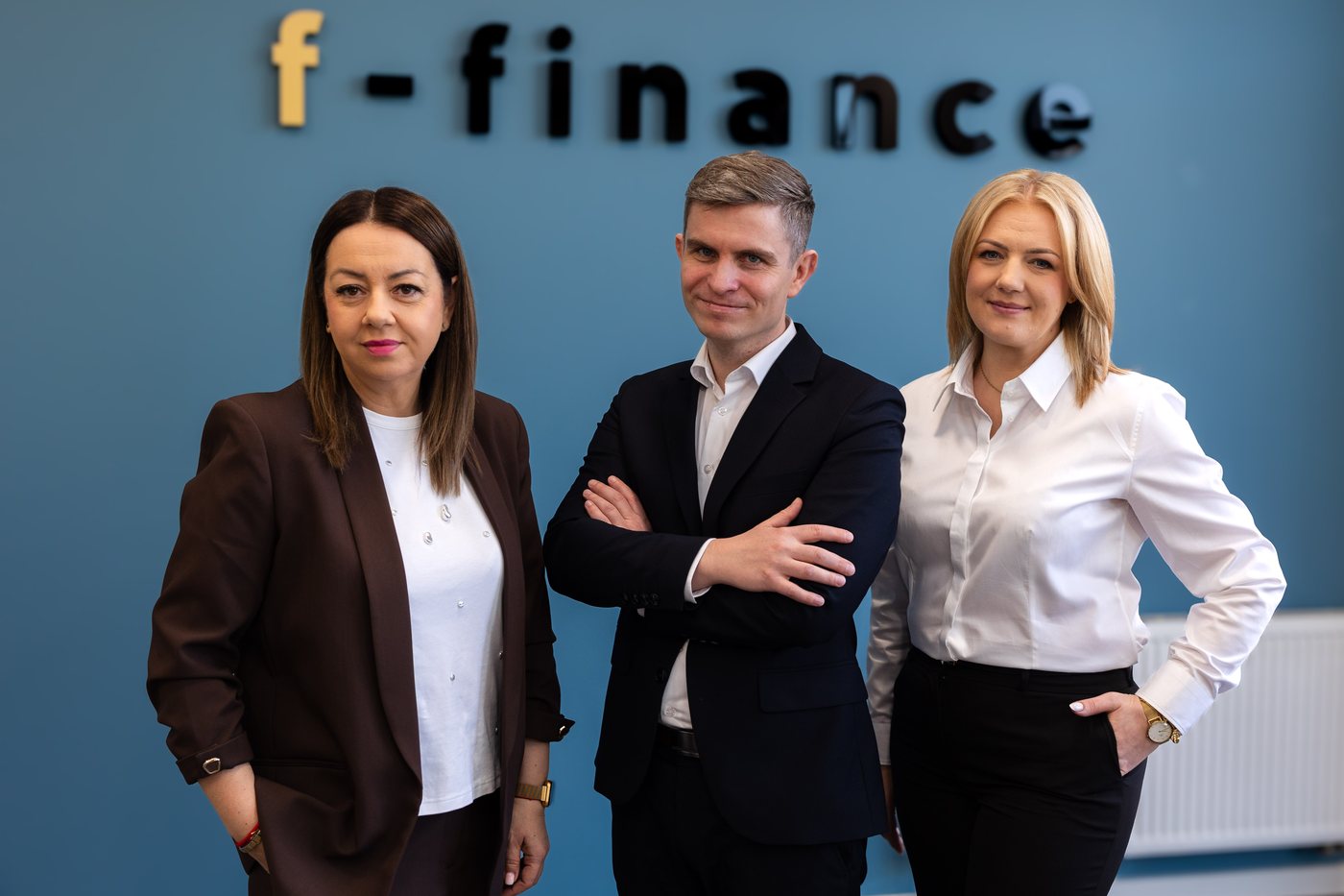 Zespół F-FINANCE przy ścianie z logo firmy
